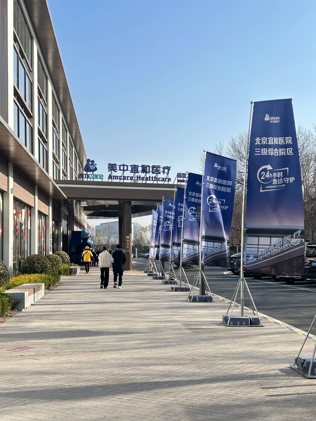 Beijing Amcare Hospital Sanyuanqiao Campus exterior with flags showing 24-hour emergency care